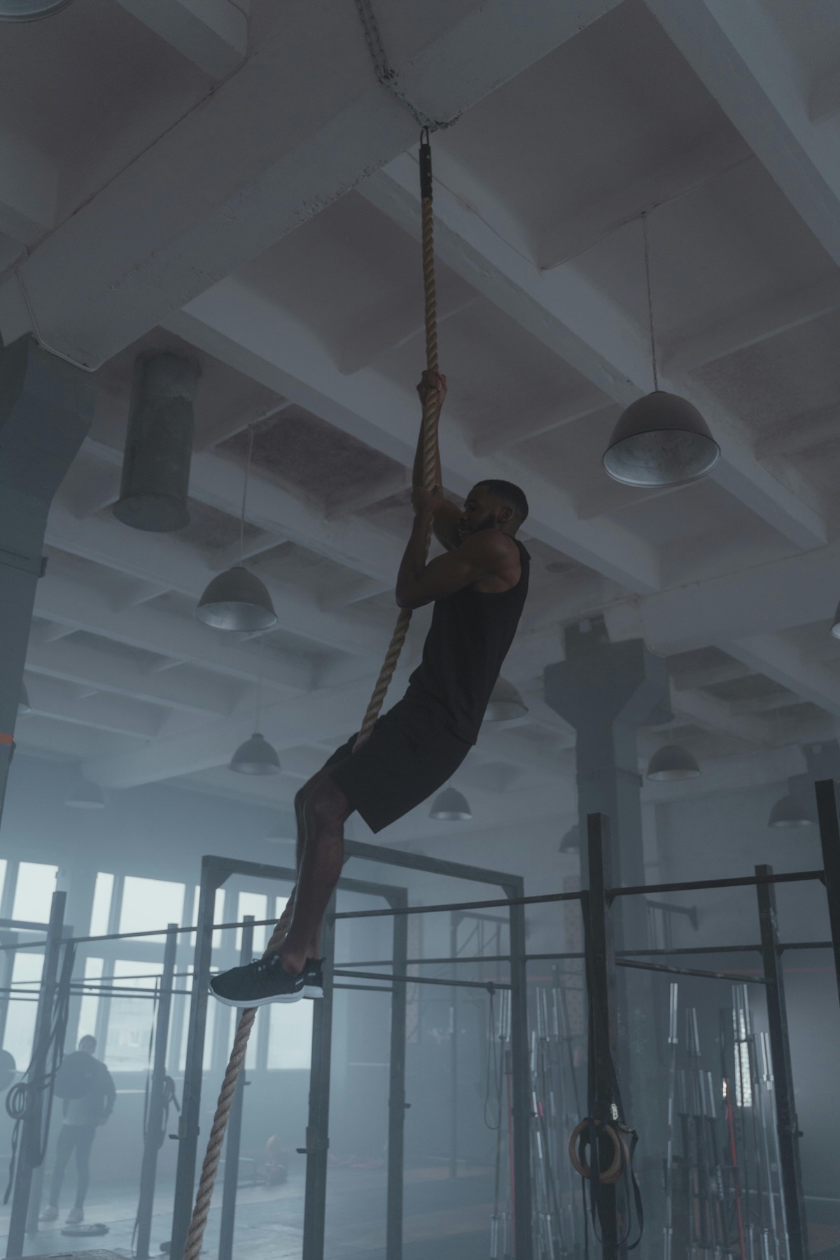 Athlete climbing a rope on a functional fitness gym floor